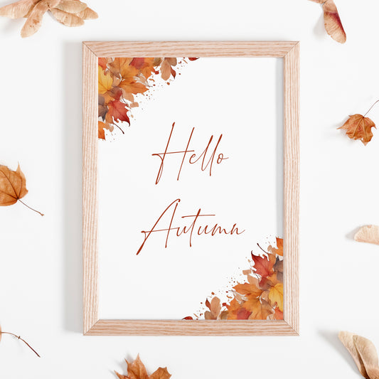 Single portrait print with the text "Hello Autumn" in a modern script font. The print is decorated by illustrations of autumn leaves, positioned to the top left and bottom right corners. Autumn shades are used across both the text and imagery.