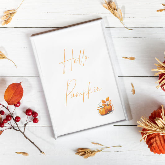 Single portrait typography print featuring the following text: Hello Pumpkin. Text is in an autumnal shade of orange and in a contemporary script font. The print is complemented by a small illustration of pumpkins to the bottom right.