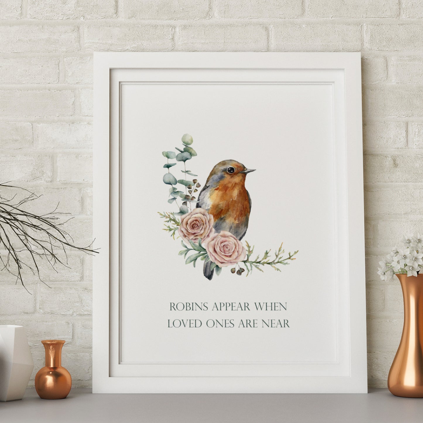 Single portrait print featuring an illustration of a robin perched on foliage and two pink roses. Text below reads: Robins appear when loved ones are near. Text is deep green on a white background and in a formal upper case serif font.