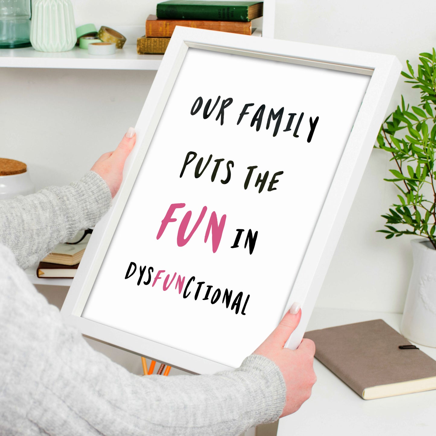 Single portrait typography print. Text reads: our family puts the fun in dysfunctional. Text is upper case and black on a white background. The word fun and the letters f-u-n in the word dysfunctional are highlighted in pink.