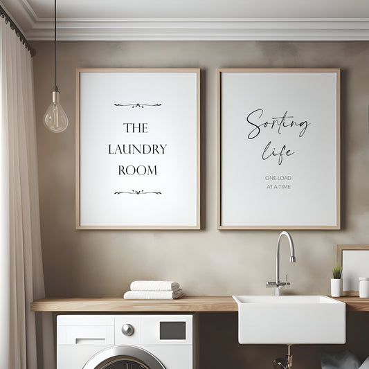 Set of 2 portrait typography prints. Print 1 reads: The Laundry Room. Print 2 reads: Sorting life one load at a time. Text is black on a white background. Styling is modern and elegant.