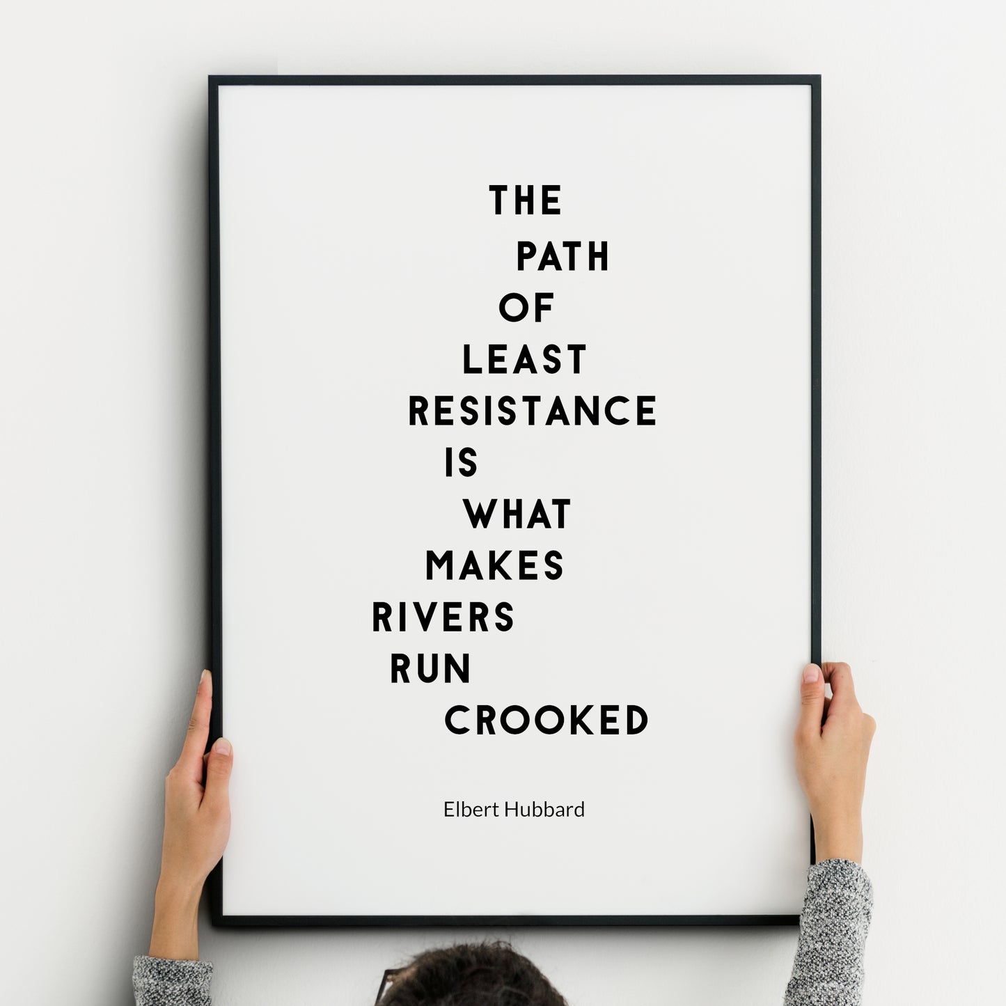 Single portrait typography print, featuring the following quote from Elbert Hubbard: The Path Of Least Resistance Is What Makes Rivers Run Crooked. The quote is in a strong upper case font, one word per row. Text is black on a white background.