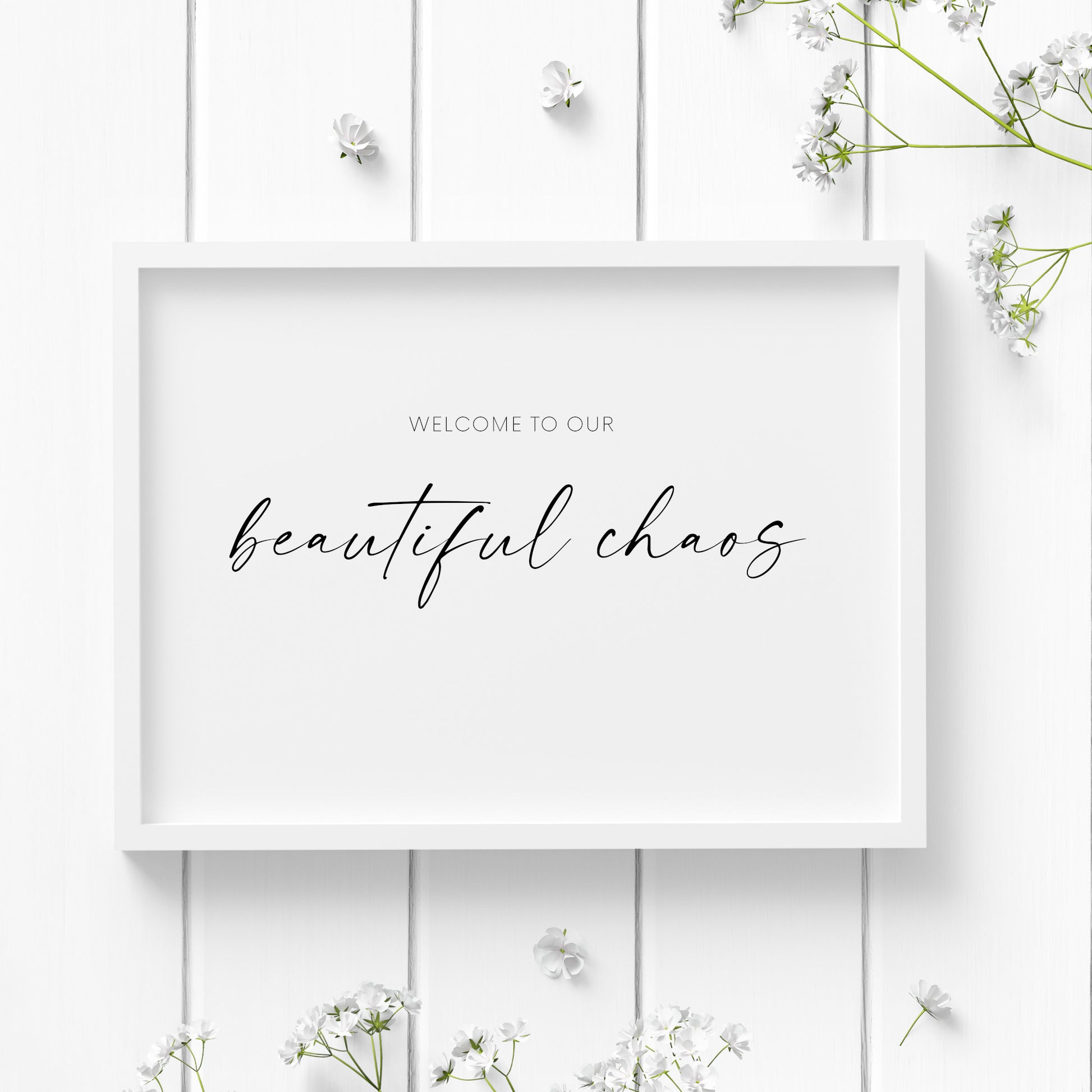 Single landscape typography print. Text reads: Welcome to our beautiful chaos. The words beautiful chaos are positioned prominently in an elegant script font. Remaining text is in a small sans serif font. Text is black on a white background.