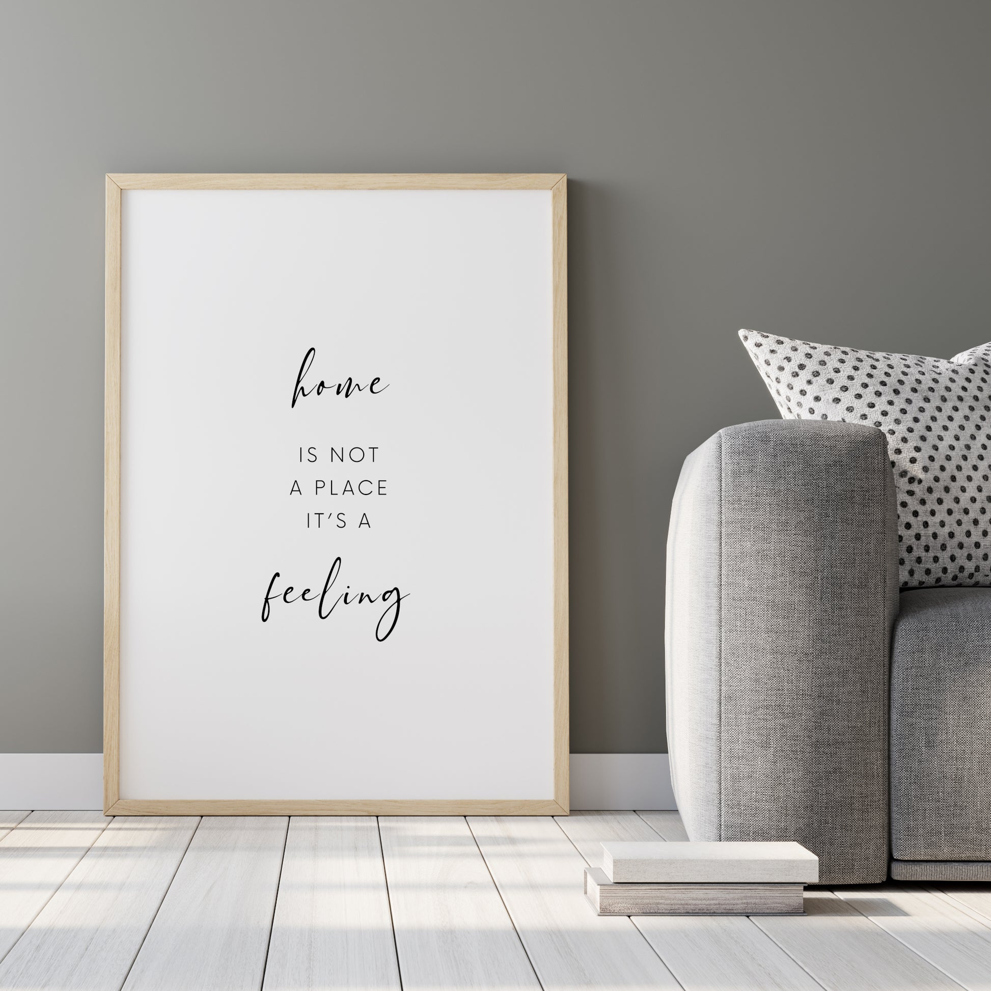 Single portrait typography print shown in a kitchen setting. Quote reads: Home is not a place it's a feeling. Text is black on a white background.