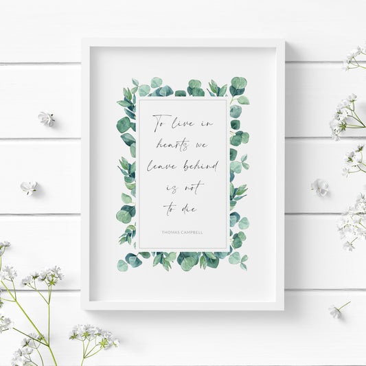 Single portrait print featuring the quote "To live in hearts we leave behind is not to die" with an attribution to Thomas Campbell. Text is black on a white background and within a rectangular border of eucalyptus leaves.