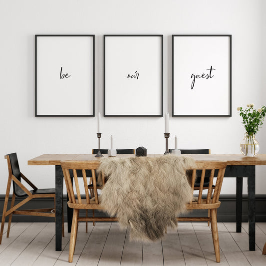 Set of 3 portrait typography prints. Text reads: be our guest. The text is distributed across the 3 prints, with one word on each. All text is in a striking script font, black on a white background.