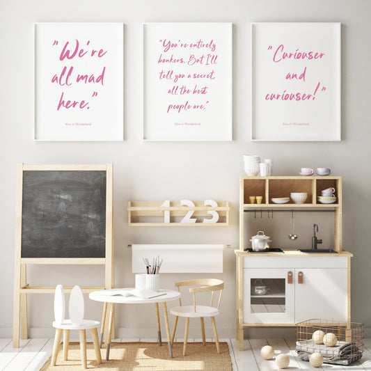 Set of 3 Alice-In-Wonderland themed prints. The quotes on the respective prints reads: "We're all mad here.";  “You're entirely bonkers. But I'll tell you a secret, all the best people are.”; "Curiouser and curiouser!". All text is pink on a white background and in a slightly grunge script font.