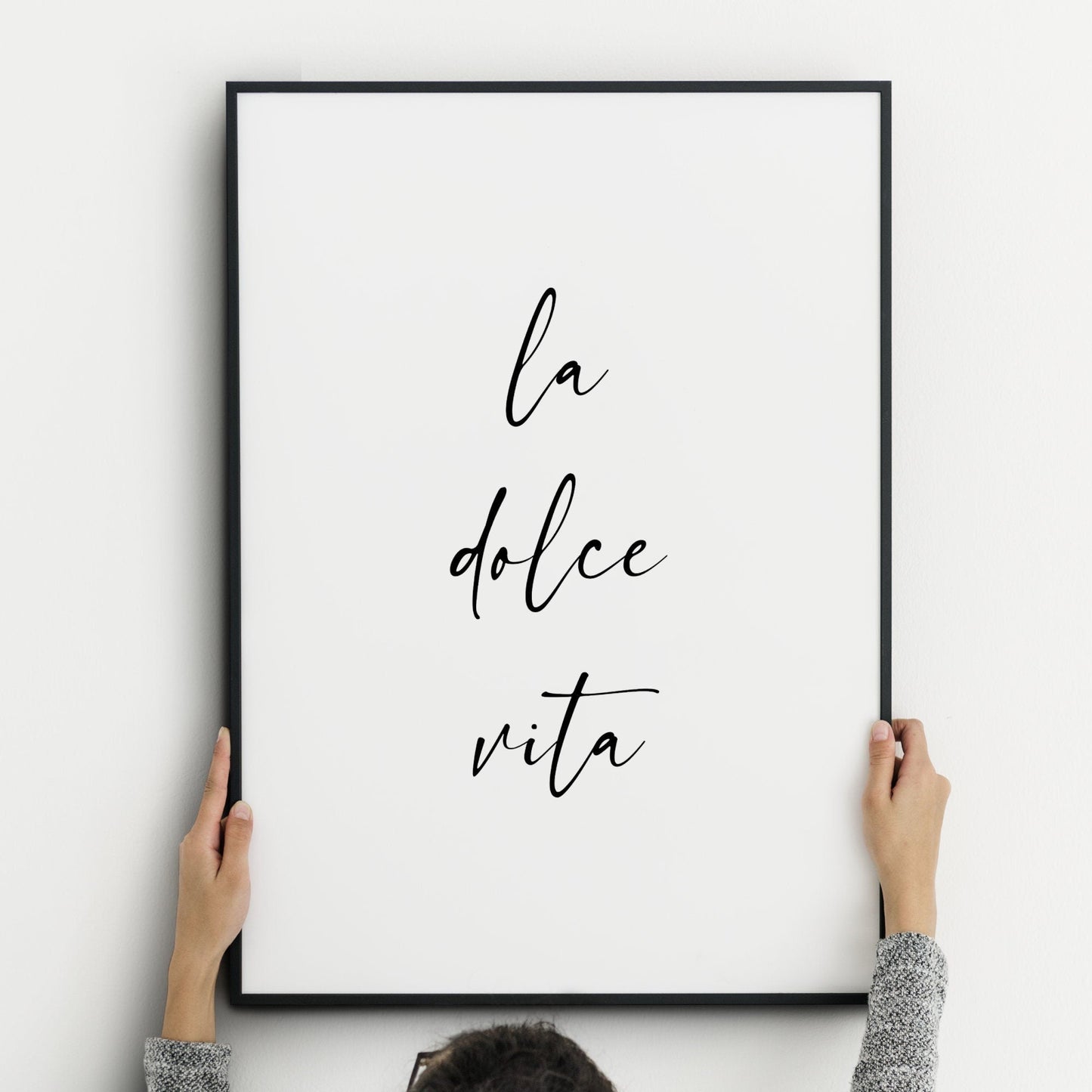 Single portrait typography print featuring the quote: la dolce vita. The text is all lower case and in a stylish script font, with the words stacked vertically. Text is black on a white background.