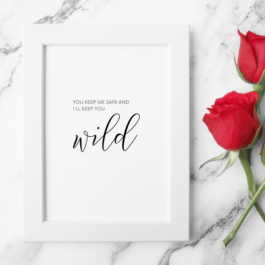 Single portrait typography print shown in a romantic setting. Quote reads: You keep me safe and I'll keep you wild. The word wild is displayed prominently in a statement script font. Text is black on a white background.