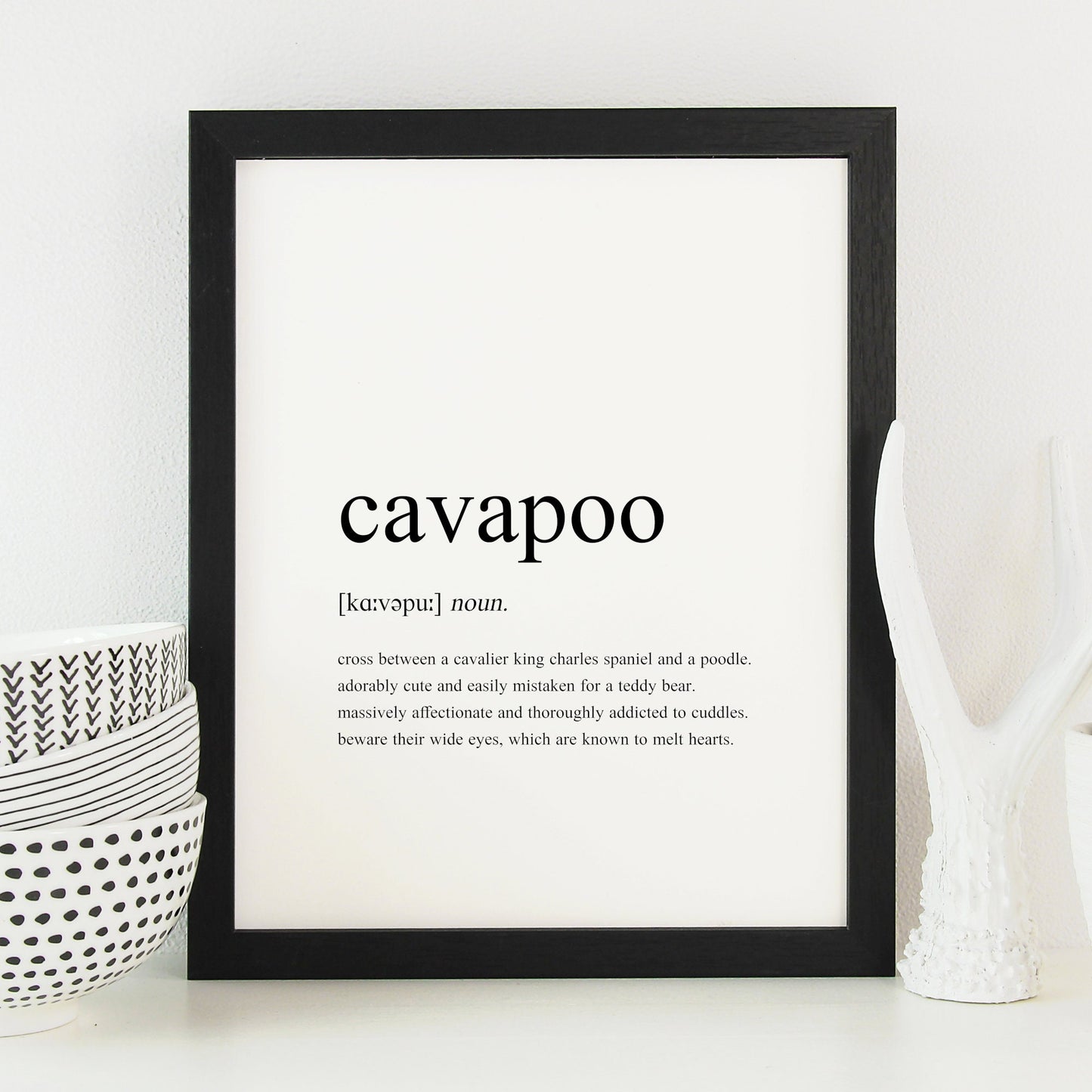 Cavapoo definition print displayed in a black frame. Styled as per a traditional dictionary definition, including the pronunciation and description. Text is factual, fun and sentimental about cavapoos. See the product description for the full text.