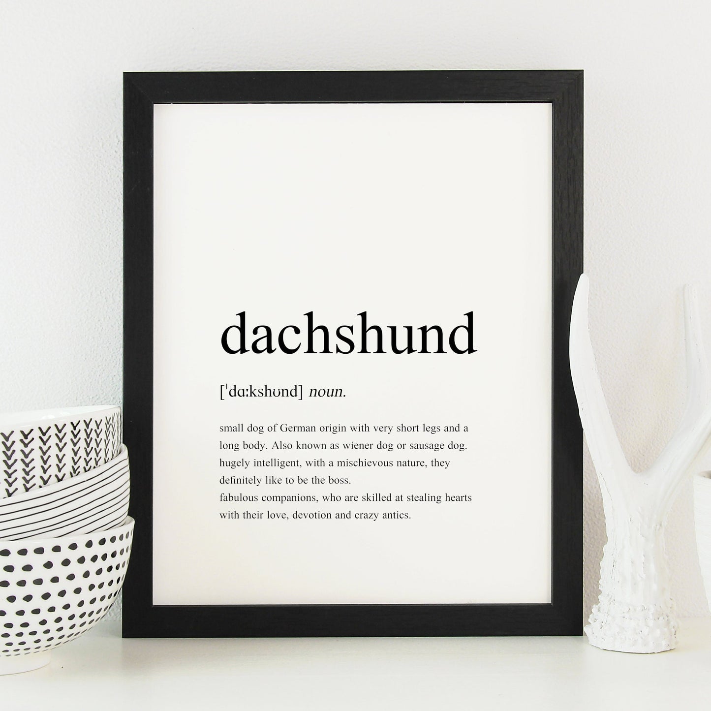 Dachshund definition print shown in a black frame. Styled as per a traditional dictionary definition, including the pronunciation and description. Text is factual, fun and sentimental about dachshunds. See the product description for the full text.