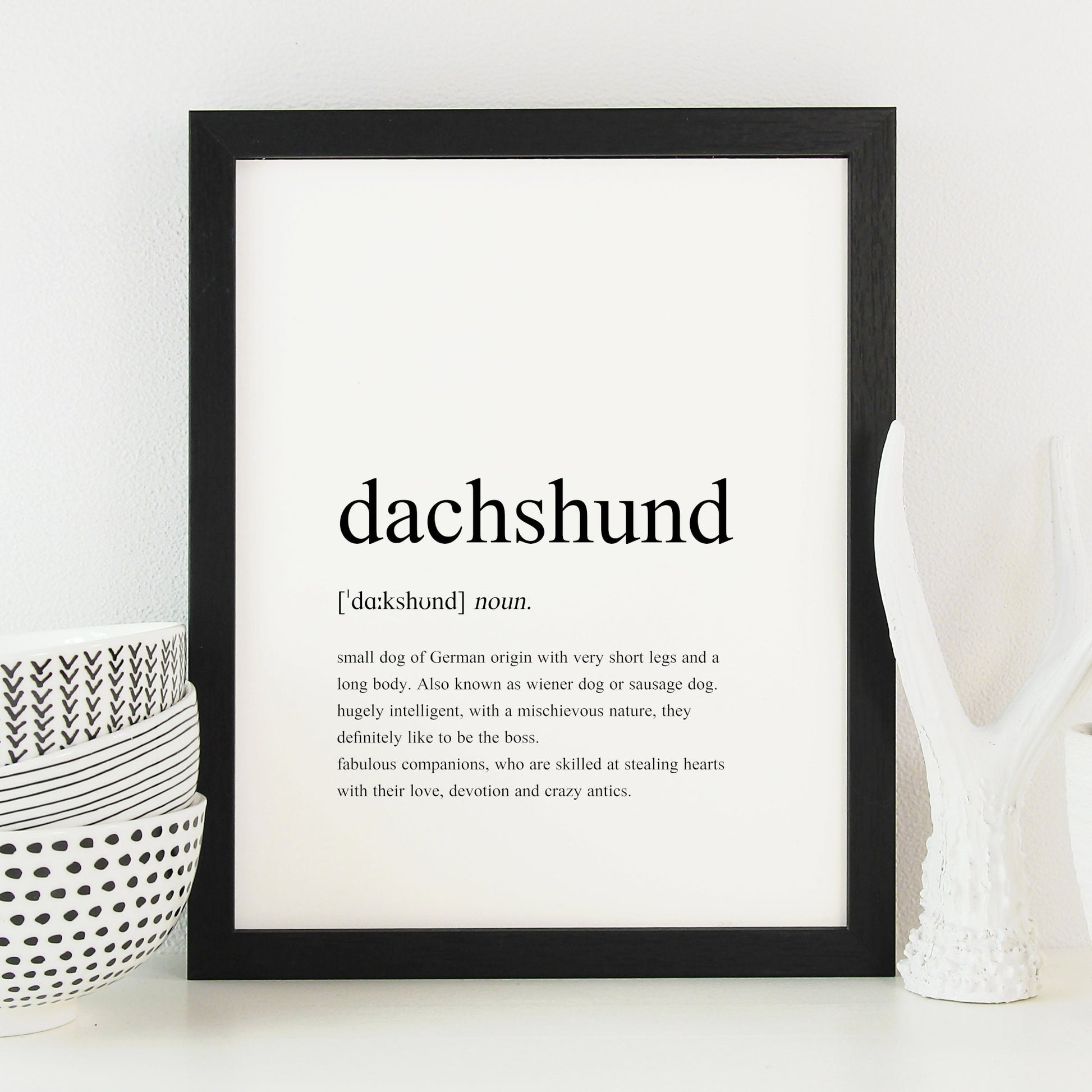 Dachshund definition print shown in a black frame. Styled as per a traditional dictionary definition, including the pronunciation and description. Text is factual, fun and sentimental about dachshunds. See the product description for the full text.