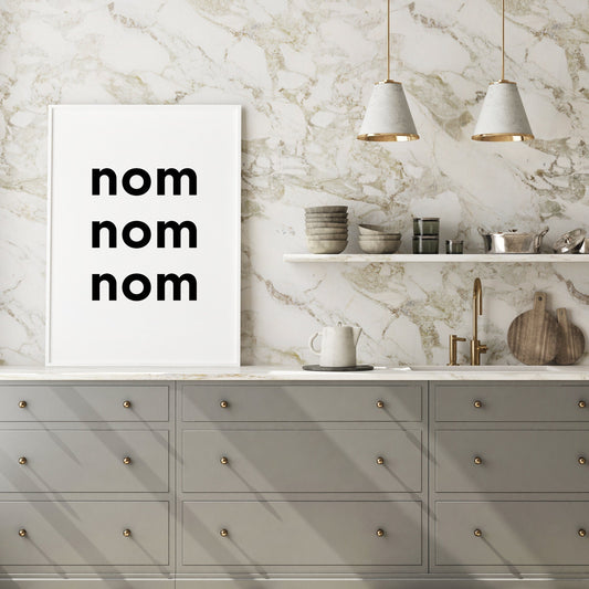 Single portrait typography print featuring the quote "nom nom nom". The words are stacked vertically in a bold lower case sans serif font. The styling is edgy and contemporary. Text is black on a white background.