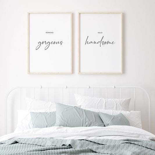 Set of 2 portrait typography prints. Print 1 text reads: Morning gorgeous. Print 2 text reads: Hello handsome. The words gorgeous and handsome are positioned prominently in an elegant script font. The prints are displayed above a master bed.