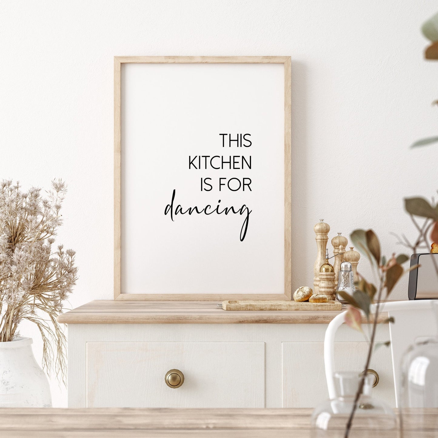 Single portrait typography print shown in a kitchen setting. Text reads: This kitchen is for dancing. The word dancing is displayed prominently in an elegant script font.