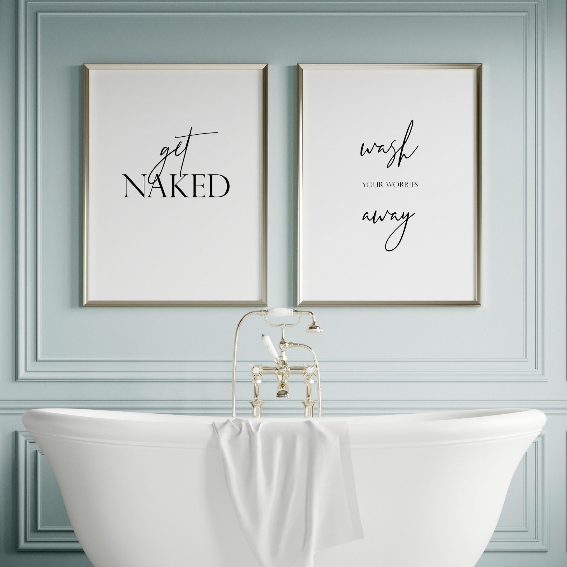 Set of 2 portrait typography prints shown side by side in a bathroom setting. Print 1 text reads: get naked. Print 2 text reads: wash your worries away. All text is black on a white background.