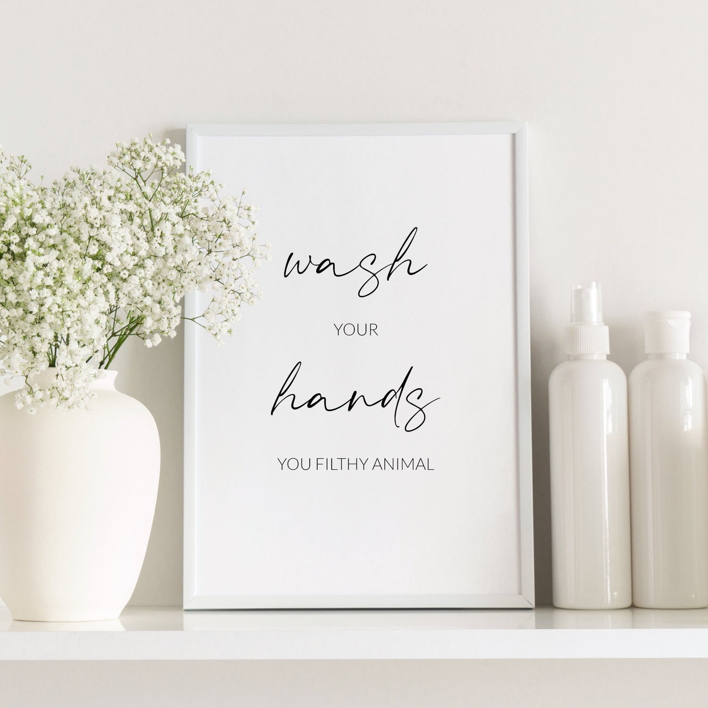 Single portrait typography print shown in a bathroom setting. Text reads: Wash your hands you filthy animal. The words wash and hands are  displayed prominently in an elegant script font.