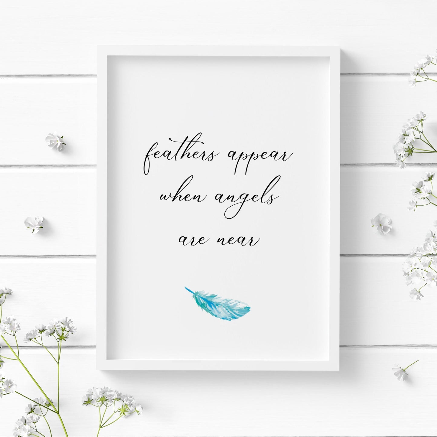 Single portrait typography print. Text reads: feathers appear when angels are near. All text is in lower case and in an elegant script font. A pale blue feather is positioned below the text. Text is black on a white background.