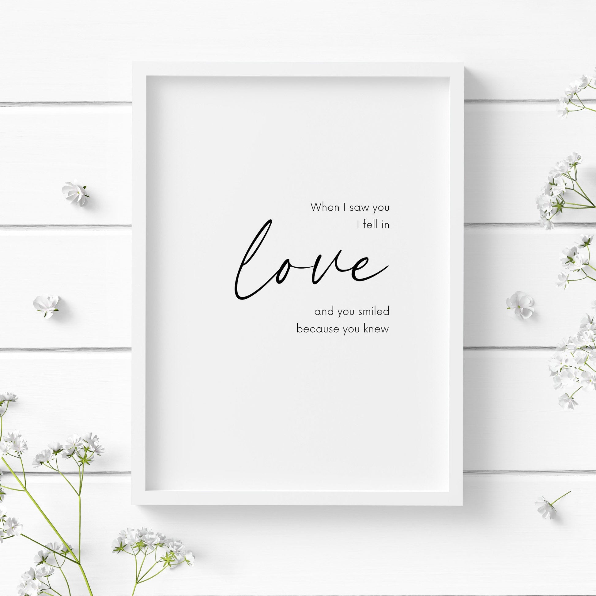 Romantic typography print, with the quote: When I saw you I fell in love and you smiled because you knew.  The word love is displayed prominently in an elegant script font. Orientation is portrait and text is black on a white background.