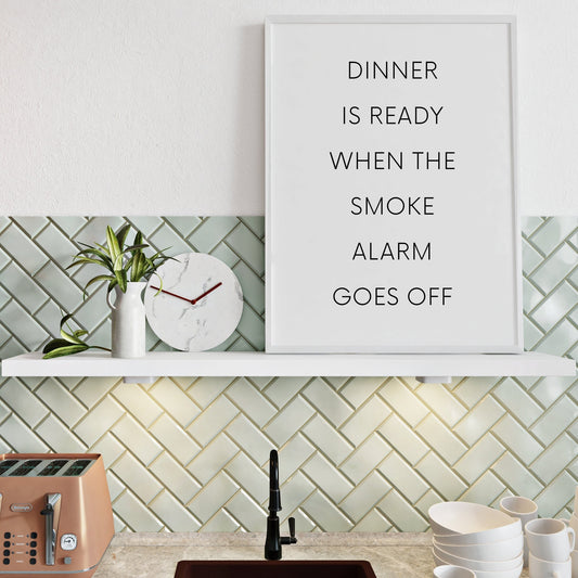 Single portrait typography print for the kitchen. Text reads: Dinner is ready when the smoke alarm goes off. The text is all capitals and in a fine sans serif font. The perfect gift for anyone with a track record of culinary disasters.