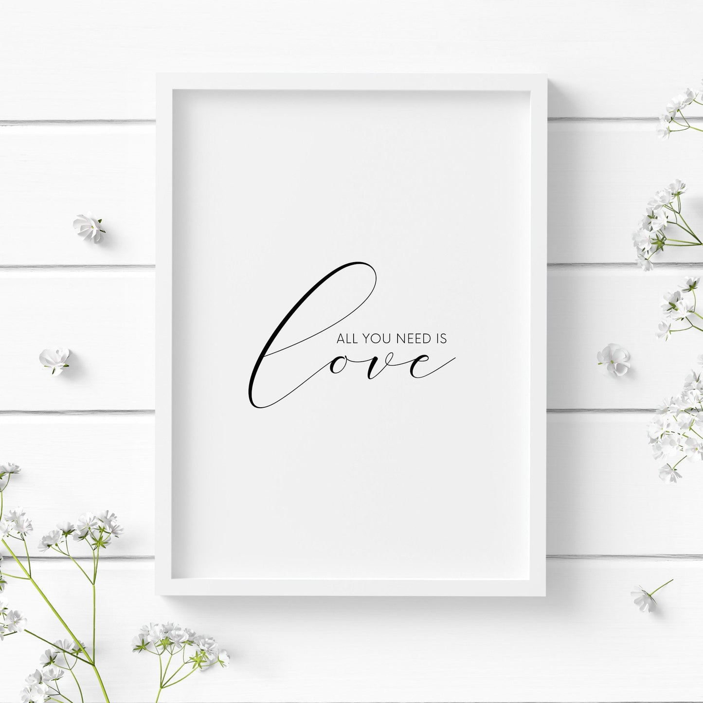 Single portrait typography print. Text reads: All you need is love. The word "love" is positioned prominently in an elegant script font. Text is black on a white background. It makes the perfect Valentine's Day gift.