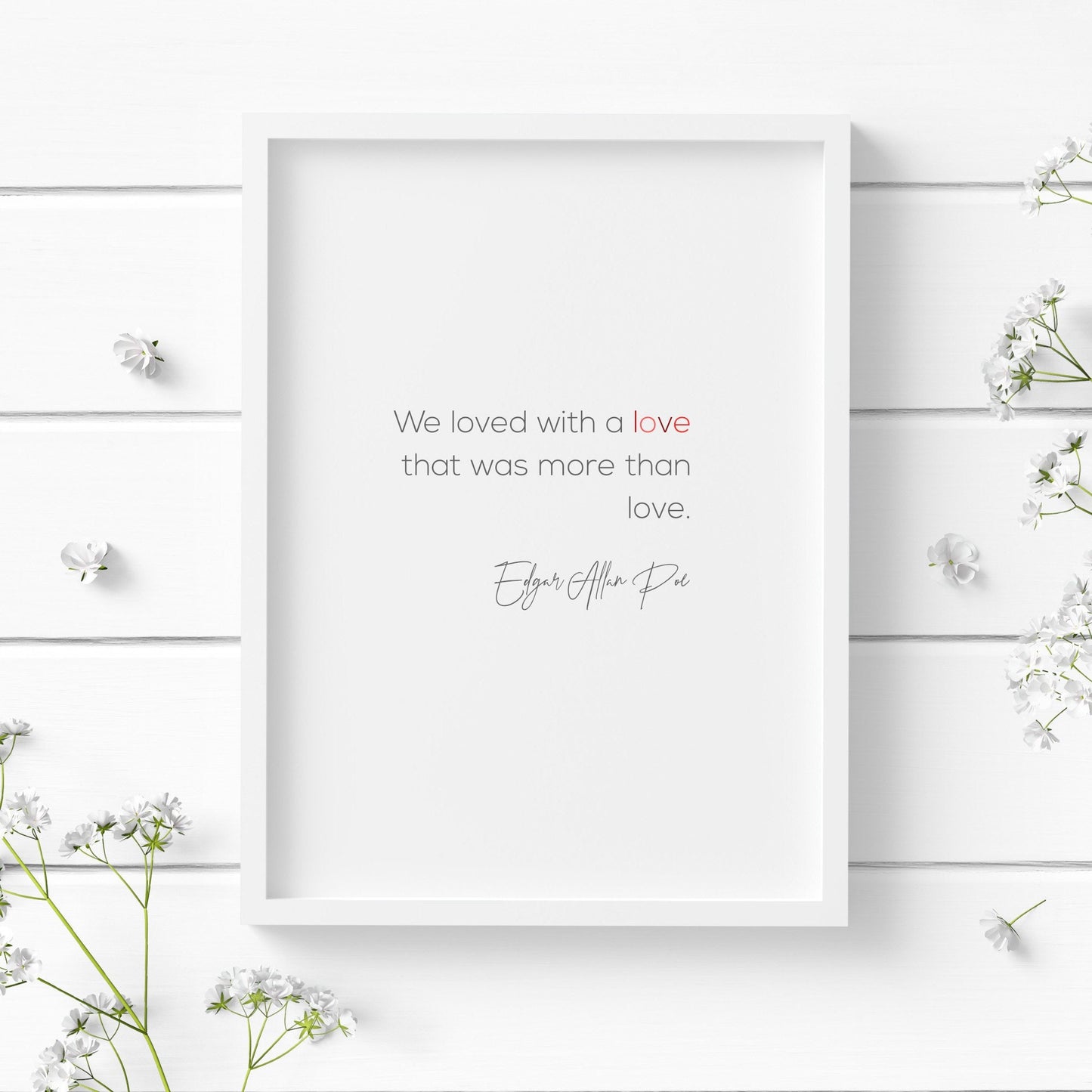 Romantic typography print. Text reads: We loved with a love that was more than love. Edgar Allan Poe. Body text is in a modern sans serif font, with the attribution in a striking script font. Text is black with the word love in shades of red.