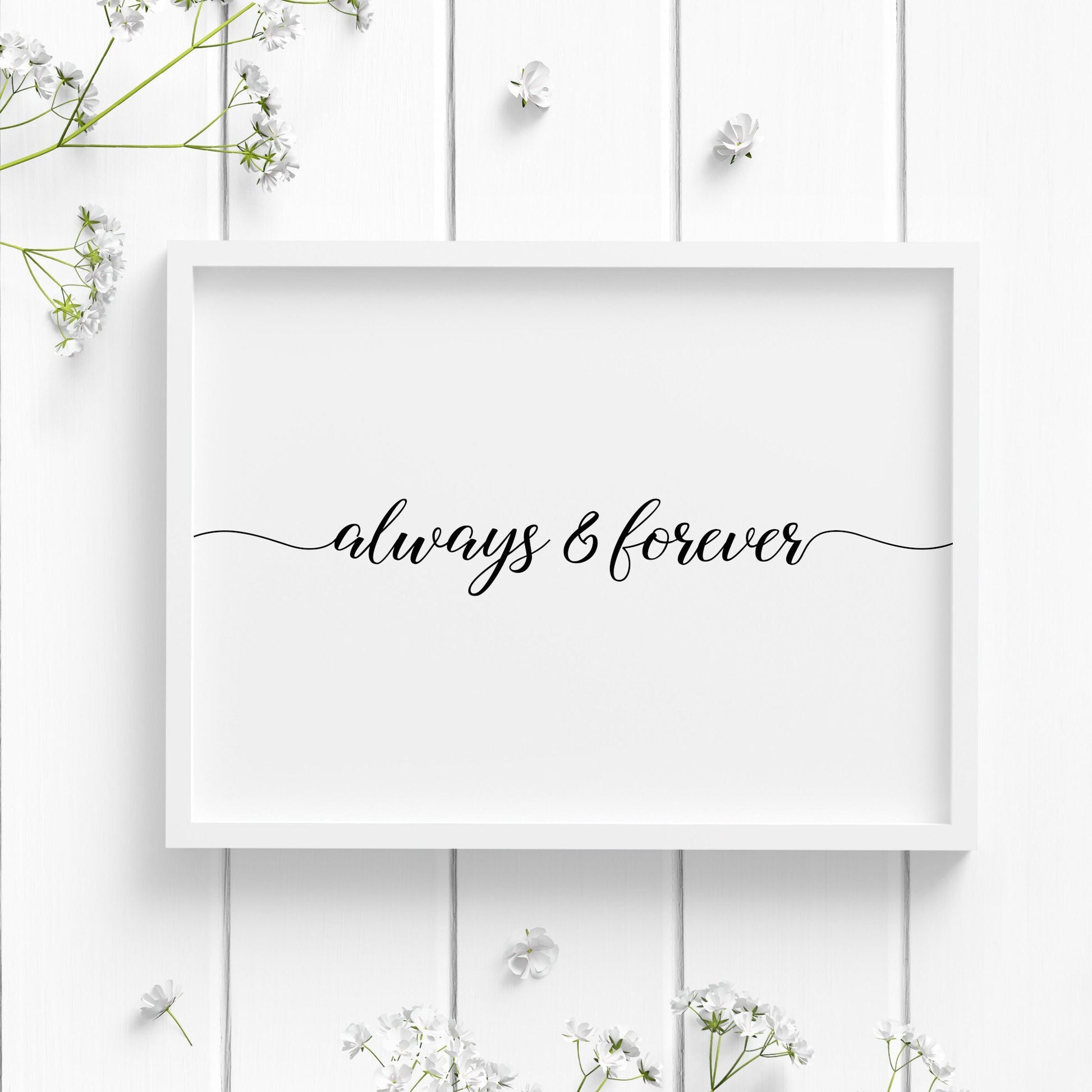 Single landscape typography print. Text reads: always & forever. Text is in a stylish script font, with the leading and trailing edges of the quote reaching to the outer edges of the let and right of the print. Text is white on a black background.