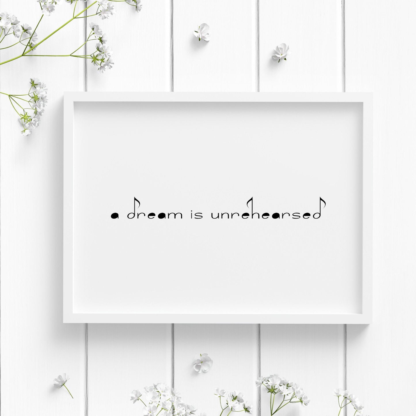 Single landscape typography print featuring the quote "a dream is unrehearsed" from Yehudi Menuhin. A music-themed font is used, which sees various letters presented as musical notes. Text is black on a white background.